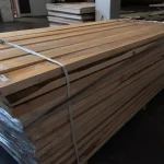 Large stack of edged spruce boards secured with packaging straps in a warehouse.