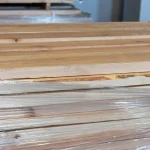 Side view of a stack of edged spruce boards wrapped in protective stretch film.