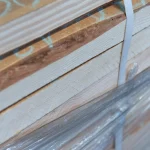 Side view of a neatly stacked bundle of edged spruce boards secured with a white strap.