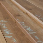 Spruce boards stacked together, showing chalk markings of dimensions on their faces.