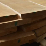 Close-up of the ends and edges of stacked edged alder boards showing thickness.