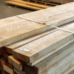 Close-up of the top of a strapped ash lumber stack showing handwritten dimensions and markings.