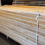 Long side profile of a high-quality stack of edged ash boards showing uniform thickness and straight edges.