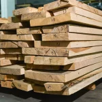 Stacked ash lumber boards showing numbered ends for inventory tracking.