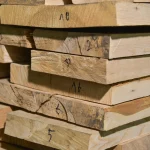 Close-up of the ends of stacked ash boards with handwritten numbers.