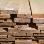 Front view of the ends of stacked edged ash lumber showing wood grain texture.
