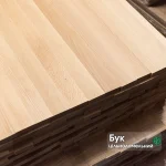 Close-up of a stack of solid-lamella beech edge-glued panels showing the smooth wood grain.