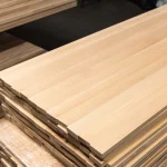 Perspective view of a 20mm solid beech furniture board lying on a stack in a warehouse.