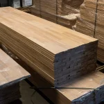 A large stack of finger-jointed beech wood panels stored in a warehouse.