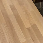 Top-down view of the smooth, sanded surface of a finger-jointed beech furniture board.