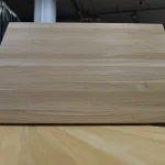 Frontal view of a solid oak furniture board standing vertically, showcasing its uniform texture.
