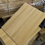A person holding a solid oak edge-glued panel, showcasing its size and surface quality.