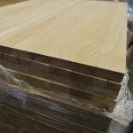 Close-up of the ends of stacked 20mm solid oak panels wrapped in protective film.