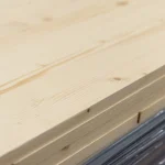 Close-up of the edge and corner of an 18mm solid-lamella pine furniture board showing the thickness.