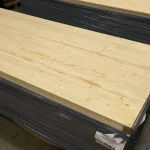 Stack of wrapped solid-lamella pine furniture panels in a warehouse ready for shipping.