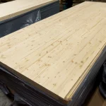 Stack of finished 18mm solid-lamella pine edge-glued panels in a workshop.