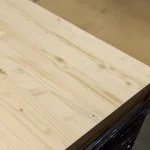 Corner of a solid-lamella pine furniture panel showing distinct wood grain and clean edges.