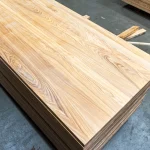 High-angle view of a stack of finished full-lamella ash furniture panels in a workshop.