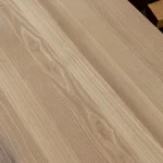Close-up texture of a solid ash furniture panel highlighting the beautiful natural grain patterns.