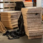 Tall stacks of ash edge-glued panels stored in a warehouse with protective packaging.