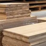 Close-up of the smooth surface and solid-lamella edges of stacked ash furniture panels.