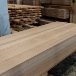 Perspective view of a solid ash furniture panel stack with raw lumber in the background.
