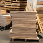 Full stack of ash edge-glued panels on a wooden pallet in a spacious warehouse.