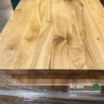 Close-up of the natural wood grain and knots on a solid ash edge-glued furniture panel.