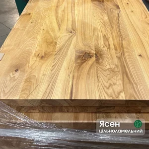 Close-up of the natural wood grain and knots on a solid ash edge-glued furniture panel.