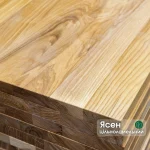 Close-up of stacked solid-lamella ash edge-glued panels showing the end grain and natural wood texture.