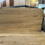 A worker holding a large solid-lamella ash furniture board showing its full surface.