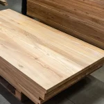 Stack of rustic ash edge-glued panels stored on a pallet in a workshop.
