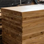 A neat stack of finished 40mm solid ash edge-glued panels in a woodworking workshop.