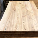 Top-down view of a solid-lamella ash panel showcasing natural rustic wood grain and knots.