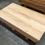 High-angle view of a stack of 40mm thick solid ash furniture panels.