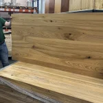 Side profile and surface of a solid ash furniture panel held next to a stack.