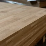 Side angle of stacked oak boards showing the 18mm thickness and finger-jointed edge profile.