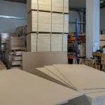 Warehouse storage area with large stacks of blockboards and HDF-faced panels.