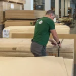 Warehouse worker securing a pack of HDF-faced blockboards with strapping bands.