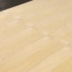 Close-up of the natural wood grain texture of white ash veneer on a blockboard.