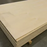 A stack of white ash veneered blockboard sheets stored in a warehouse.
