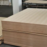 Neat stack of veneered boards showing the striped pattern of natural white ash veneer.