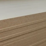Close-up of the edges of stacked veneered panels in a workshop.