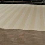 Veneered blockboard sheets stacked horizontally, highlighting the uniform ash veneer texture.