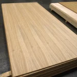 Oak veneered blockboard sheet on a stack in a warehouse, showing the smooth sanded surface.
