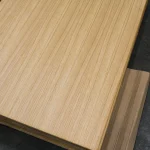Angled view of the oak veneered blockboard sheet in a stack, showcasing the uniform wood grain.