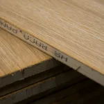 Close-up of the side edge of an oak veneered blockboard with printed manufacturer markings.