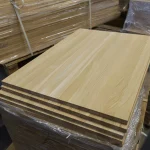 A stack of packaged oak furniture panels on a warehouse pallet.
