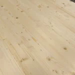 Close-up of the smooth surface of a solid-lameled pine panel with beautiful grain patterns.