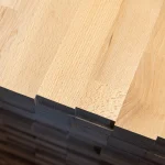 Close-up of the finger joints and edges of stacked beech furniture panels.